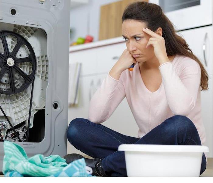 A photo showing a lady sitting by her washing machine that malfunctioned